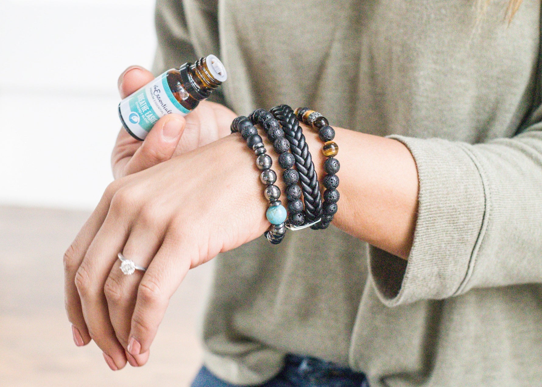 Person wearing multiple bracelets on a neutral background